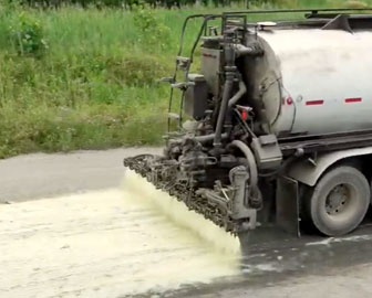 Cousco Brown truck spraying gravel roadway