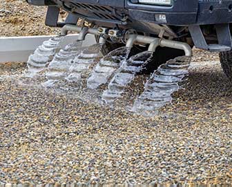 Water truck spraying gravel roadway